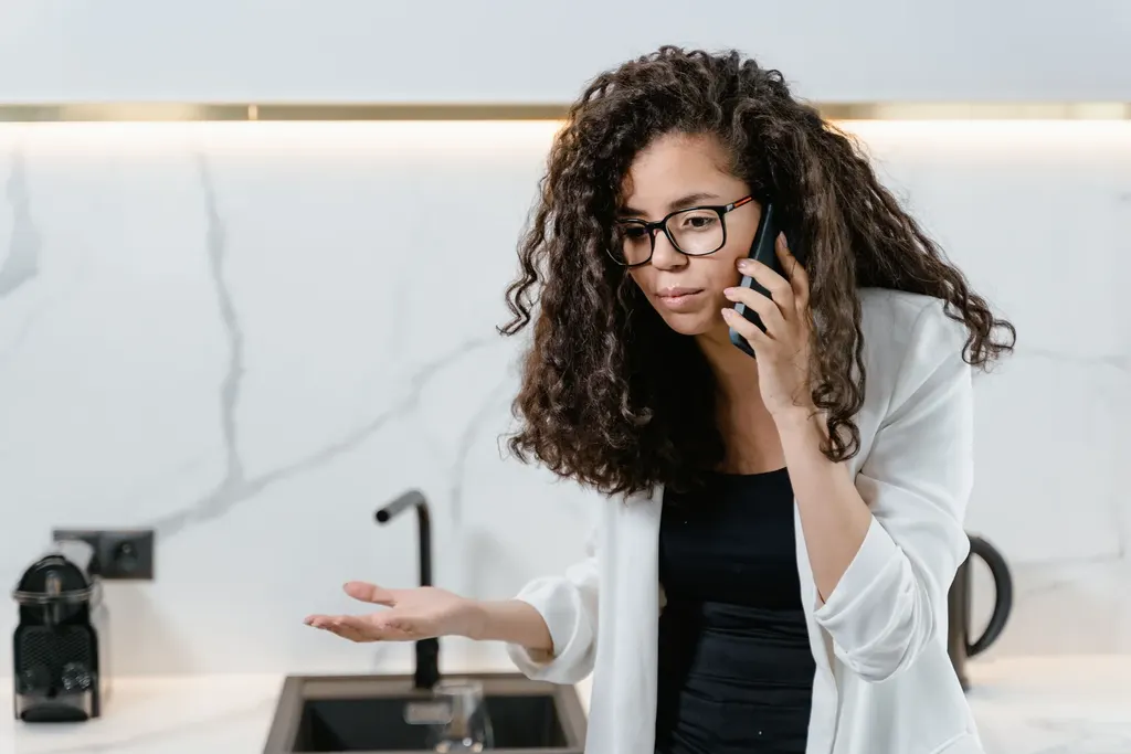 Donna al telefono mentre consulta il comparatore in cucina